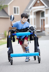 Six year old disabled boy walking in walker on street
