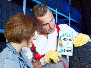 Car mechanic explains to a customer tire labeling in a garage