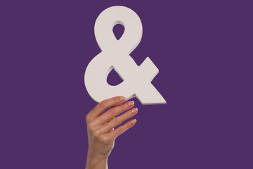 Female hand holding up an ampersand from the bottom