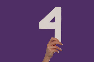 Female hand holding up the number 4  from the bottom