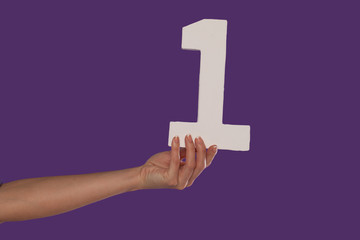 Female hand holding up the number 1 from the left