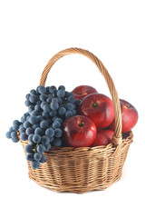 Wicker basket with red apples and blue grapes
