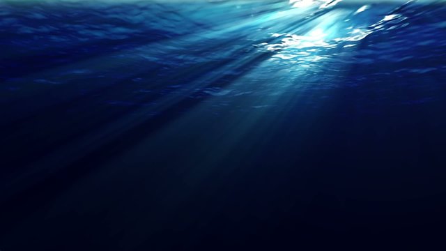 Underwater sunrays shine through the water's surface. Looping.