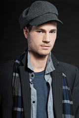 Handsome man dark winter fashion. Studio shot. Wearing cap.