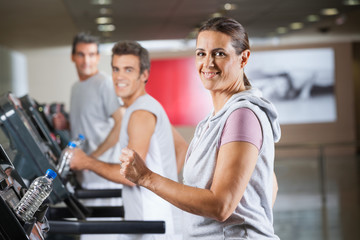 Woman And Men Running On Treadmill In Fitness Center