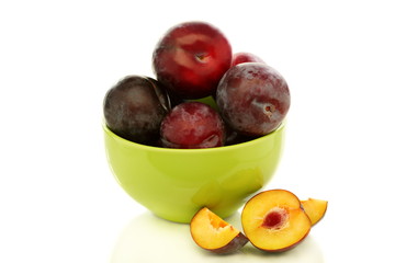 Red plums in green bowl.