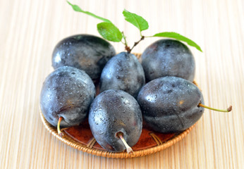 Rip plums on basket on wooden table