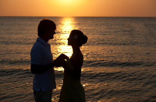 sunset silhouette of happy young lovers on the beach. honeymoon