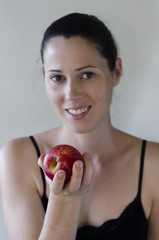 Young woman holds an apple on white background