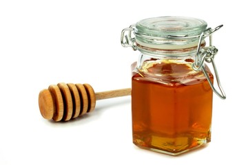 Honey in jar and dipper on white background.