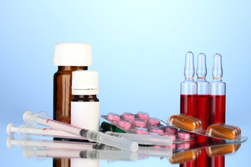 medical ampules, bottles, pills and syringes on blue background