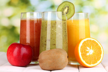 fresh fruit juices on wooden table, on green background