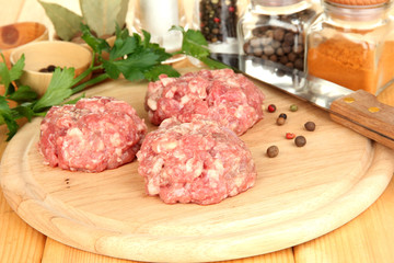 Raw meatballs with spices on wooden table