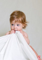 Cute baby girl bites white cloth edge