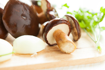 Raw mushrooms on cutting board and fresh herbs