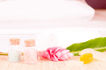 Obraz na płótnie Canvas Spa getaway with a pink ginger flower and bath salt on hotel bed