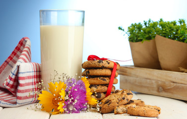 glass of milk, chocolate chips cookies with red ribbon and