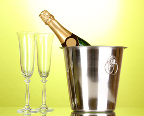 Champagne bottle in bucket with ice and glasses