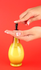 woman squeezing lotion on her hand, on red background close-up