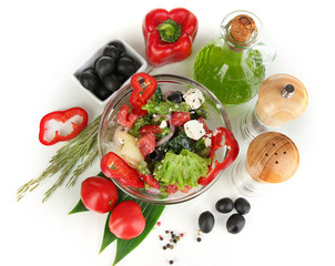 Fresh greek salad in glass bowl surrounded by ingredients for