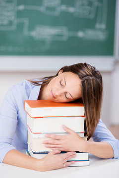 studentin schläft auf einem stapel bücher