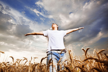Happy man standing with open arms on a wheat field © REDSTARSTUDIO
