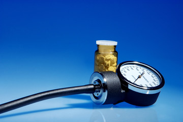 Sphygmomanometer and medicine bottle on blue background