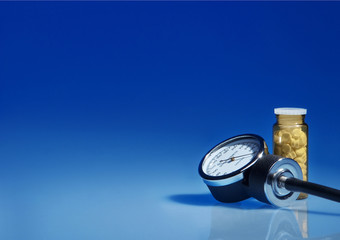 Sphygmomanometer and medicine bottle on blue background