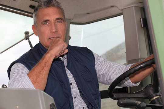 a farmer in a tractor cabin is driving