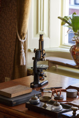 Old microscope on the desk of the doctor - obrazy, fototapety, plakaty