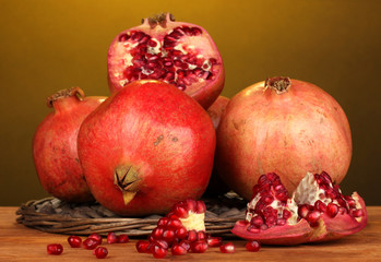 Ripe pomegranates on wicker cradle on yellow background
