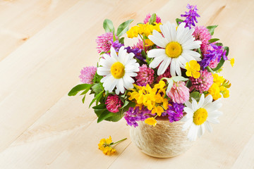 vase with bouquet of flowers and healing herbs  on wooden table