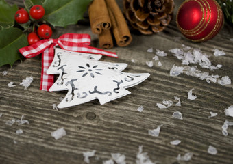 Weihnachtsbaumanhänger mit Ilex und Deko auf Holzwand mit Schnee