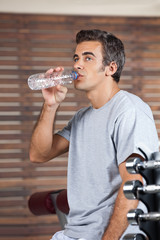 Fototapeta na wymiar Man Drinking Water From Bottle At Health Club