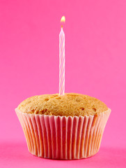 tasty birthday cupcake with candle, on pink background
