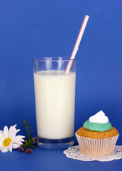 Glass of fresh new milk with cake on blue background