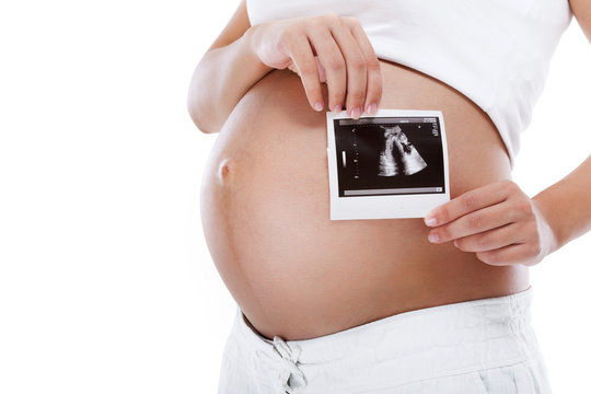 Pregnant woman holding ultrasound picture in front of belly