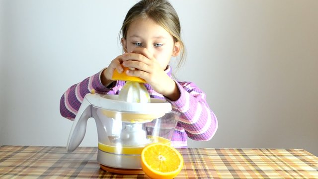 girl making fresh orange juice by juicer