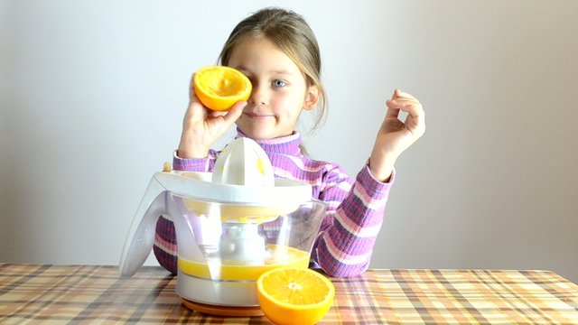 girl making fresh orange juice by juicer