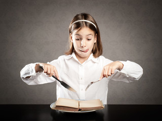 little hungry girl in front of a book