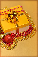 Yellow gift box with christmas baubles and beads around