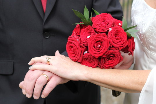 Newlywed couple hands and bouquet