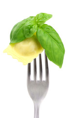 Italian ravioli with fresh basil on a fork on white background