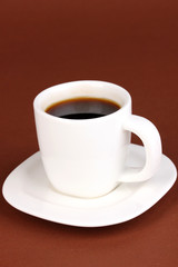 A cup of strong coffee on brown background