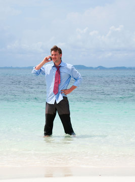 Business man calling by cell phone on the beach