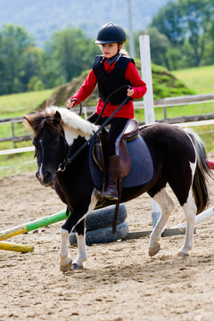 Horse riding - lovely girl is riding a pony