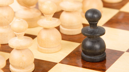 Fototapeta na wymiar Czarny pionek na drewnianej szachownicy