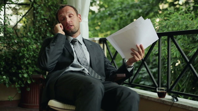 Angry businessman with cellphone after hard work on his balcony 