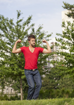 fun young man playing with his muscles outdoors
