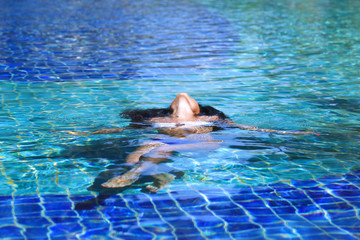 Woman floating in swimming pool